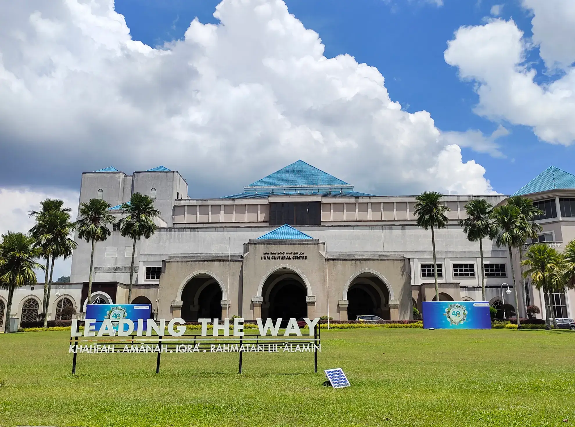 A building stands in front of a green field, representing the IIUM admission process.