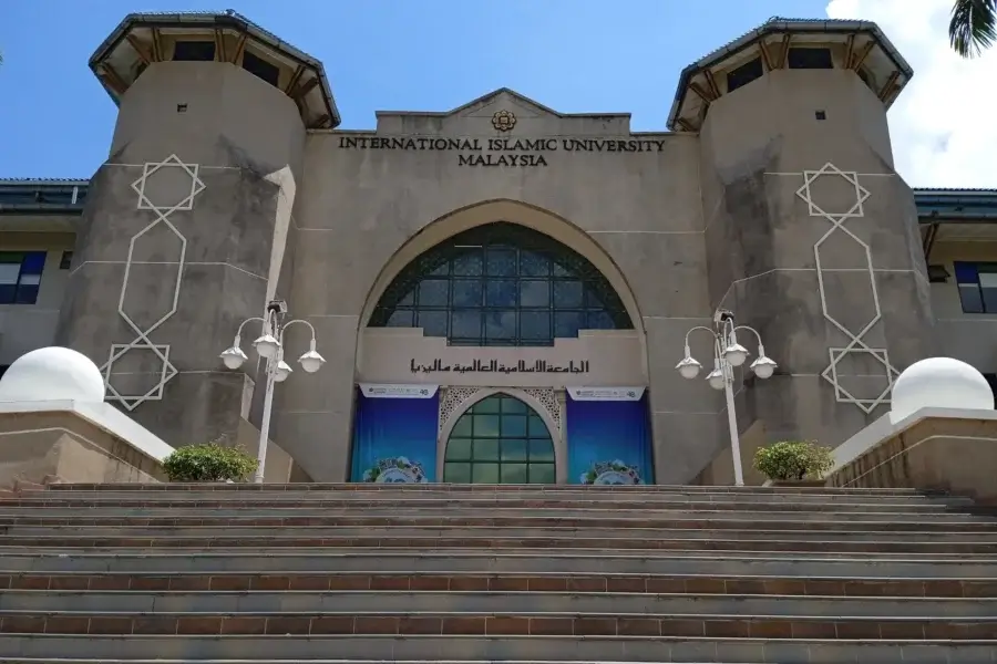 Stairs lead up to the entrance of International Islamic University Malaysia. The facade features tall towers and geometric patterns under a blue sky.